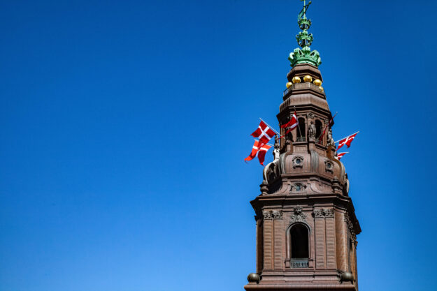 Urban scene with historical Christiansborg Palace against clear blue sky, Copenhagen, denmark